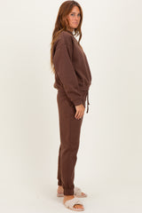 woman wearing a brown sweatshirt and matching sweatpants, styled with light-colored slippers