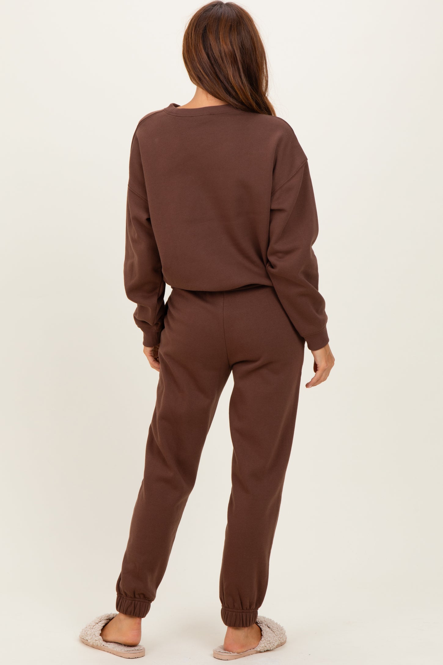 woman wearing a brown cozy sweat suit with long sleeves and jogger bottoms, viewed from the back