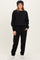 woman wearing a black sweatshirt and black jogger pants, styled with a beanie and cozy socks, standing casually