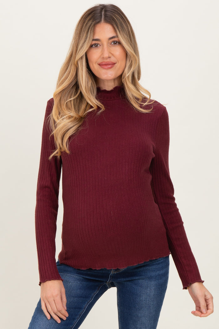 woman wearing a burgundy ribbed maternity top with a ruffled neckline and a visible baby bump