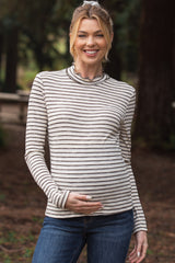 woman wearing a striped long sleeve maternity top and holding her baby bump
