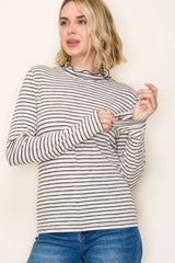 woman wearing a cream and black striped long sleeve top with a ruffled neckline and fitted sleeves