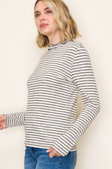 woman wearing a cream and black striped long sleeve top with a scalloped neckline and fitted silhouette