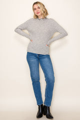 woman wearing a cream and black striped long sleeve top paired with blue jeans and black ankle boots