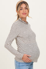 woman wearing a striped long sleeve maternity top and holding her baby bump
