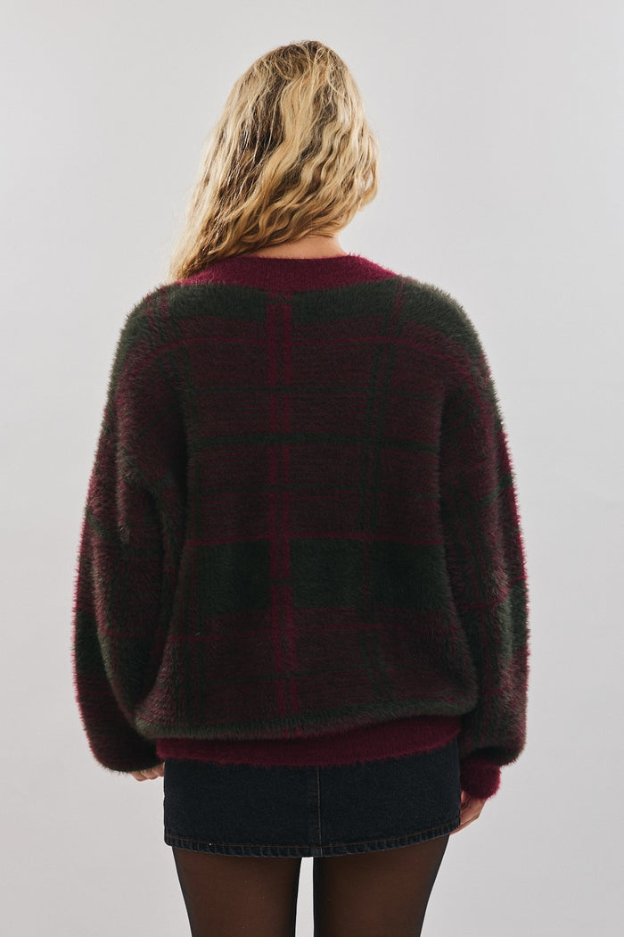 woman wearing a burgundy and green plaid oversized sweater, seen from the back with long sleeves and a relaxed fit