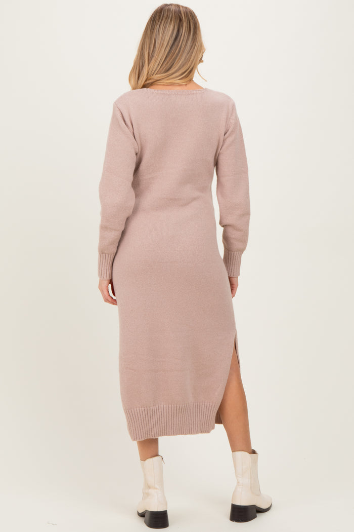 woman wearing a light pink long sleeve maternity sweater dress with side slits and a relaxed fit