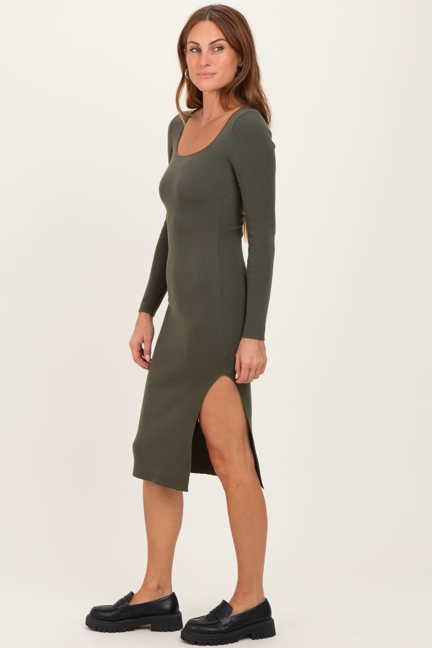 woman wearing an olive green ribbed midi dress with long sleeves and a side slit, paired with black platform shoes