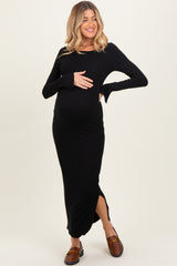 woman wearing a black long sleeve maternity dress with a side slit and holding her baby bump
