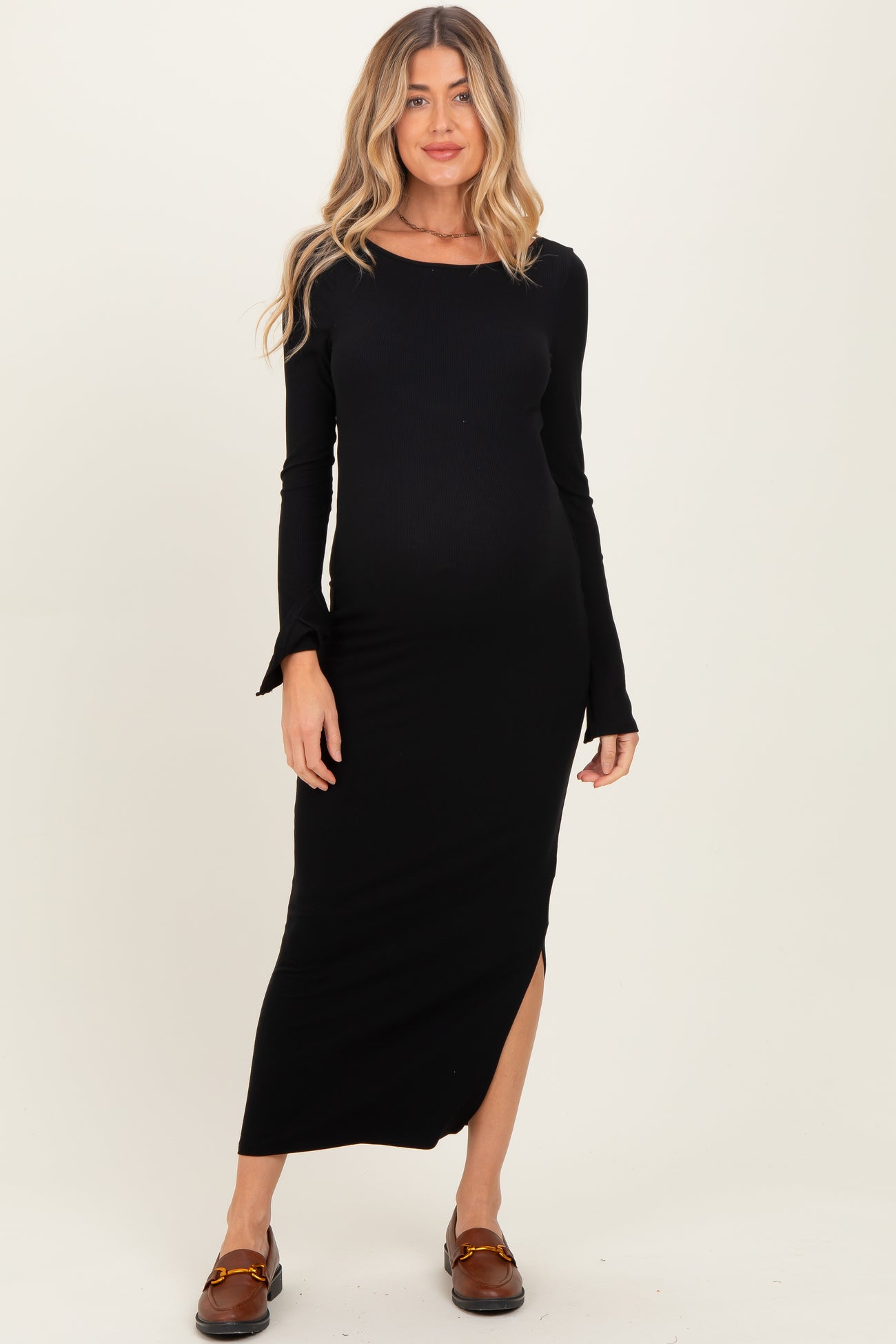 woman wearing a black long sleeve ribbed maternity dress with a side slit and a visible baby bump