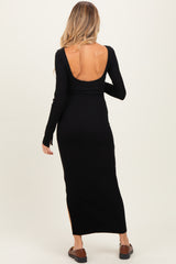 woman wearing a black long sleeve maternity maxi dress with a low back and side slits