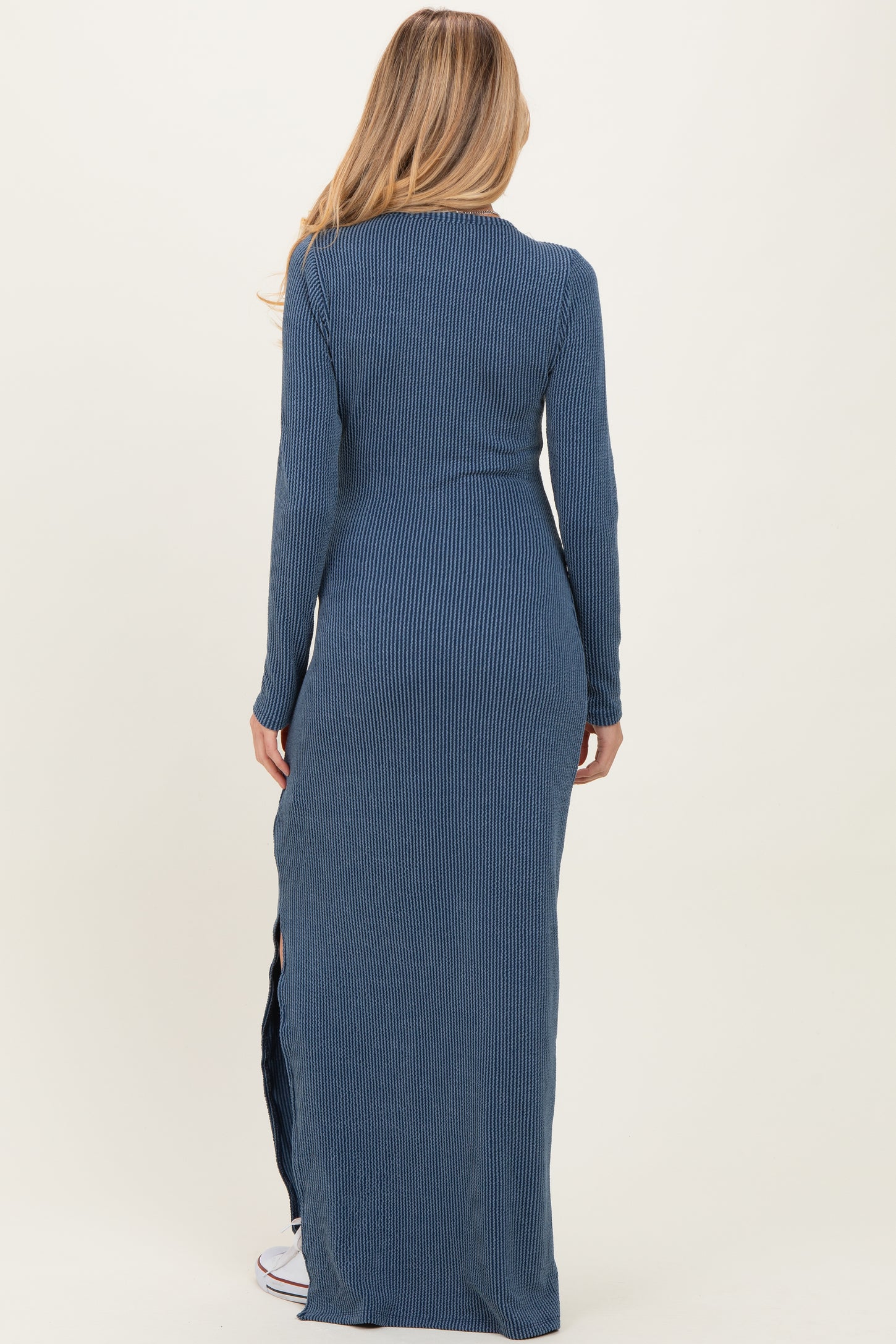 woman wearing a long navy blue ribbed maternity maxi dress with a fitted silhouette and side slits