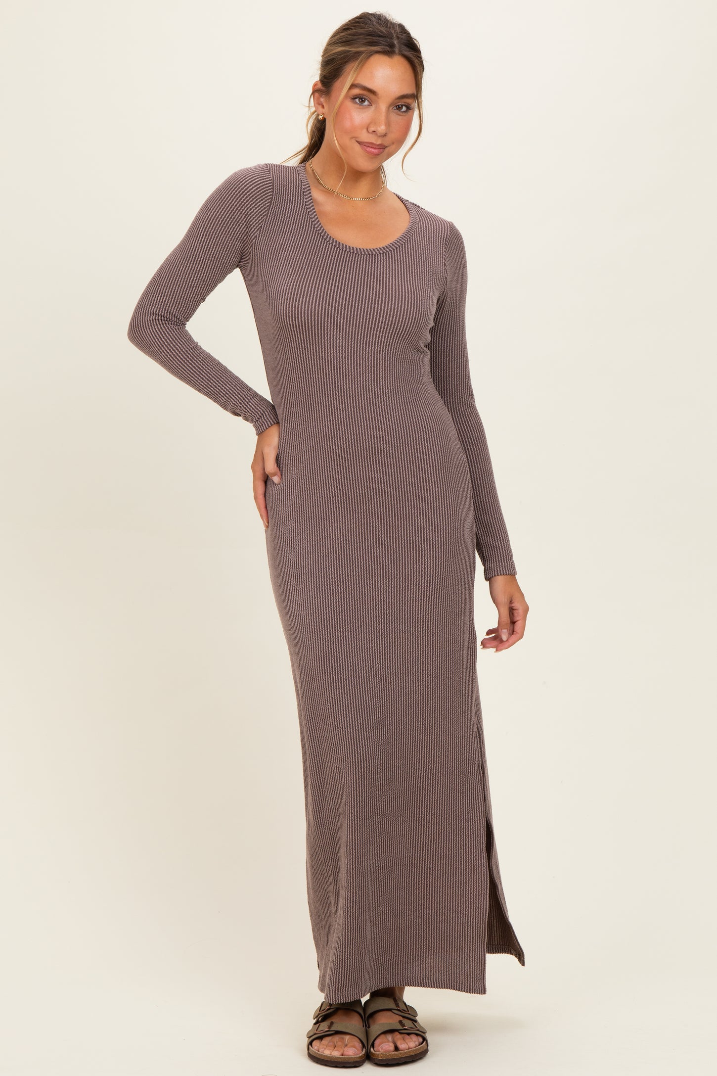 woman wearing a long sleeve brown ribbed maxi dress with side slit and a scoop neckline