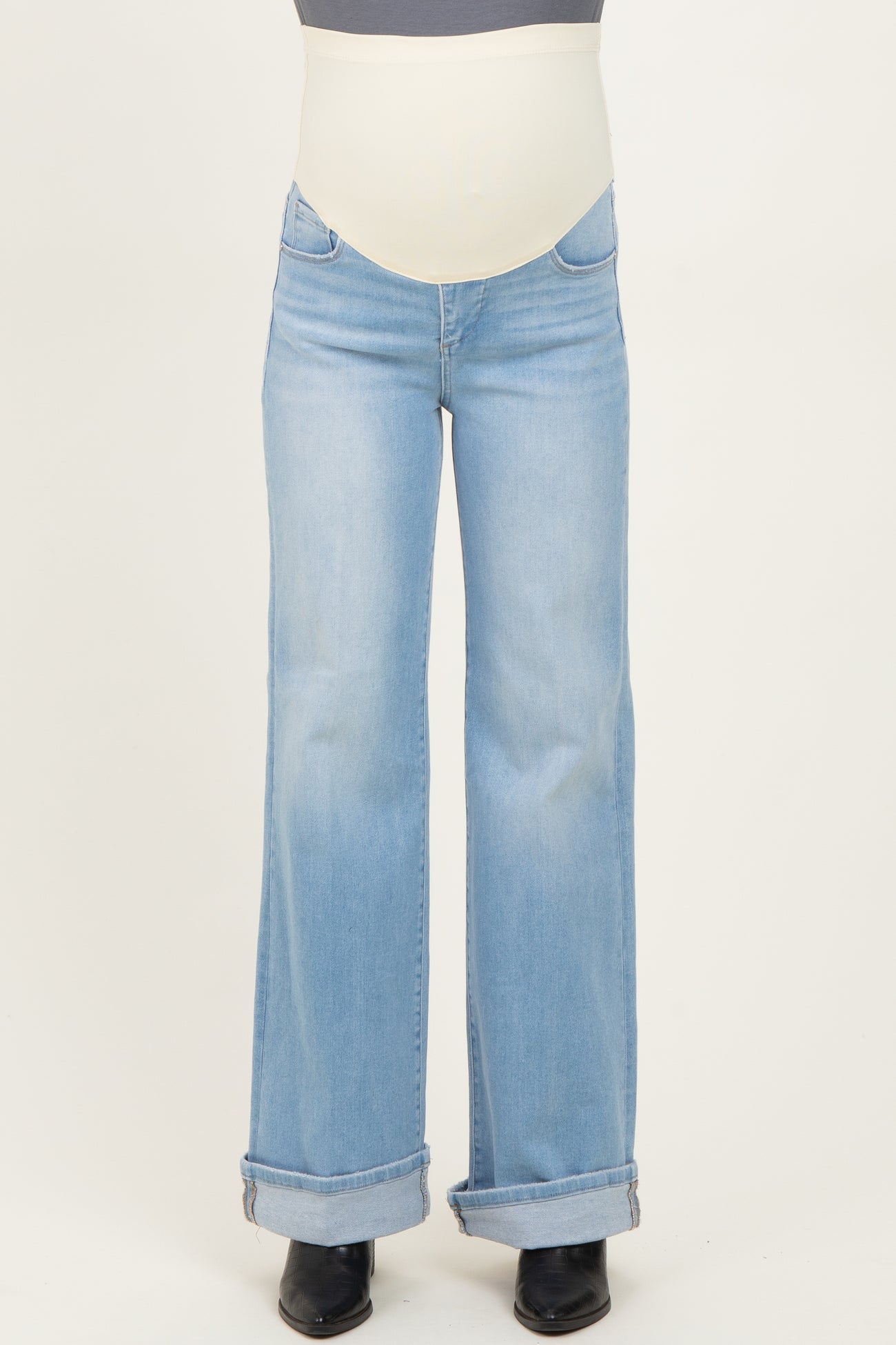 woman wearing light blue flared maternity jeans with a stretchy belly band, slightly rolled cuffs at the ankles