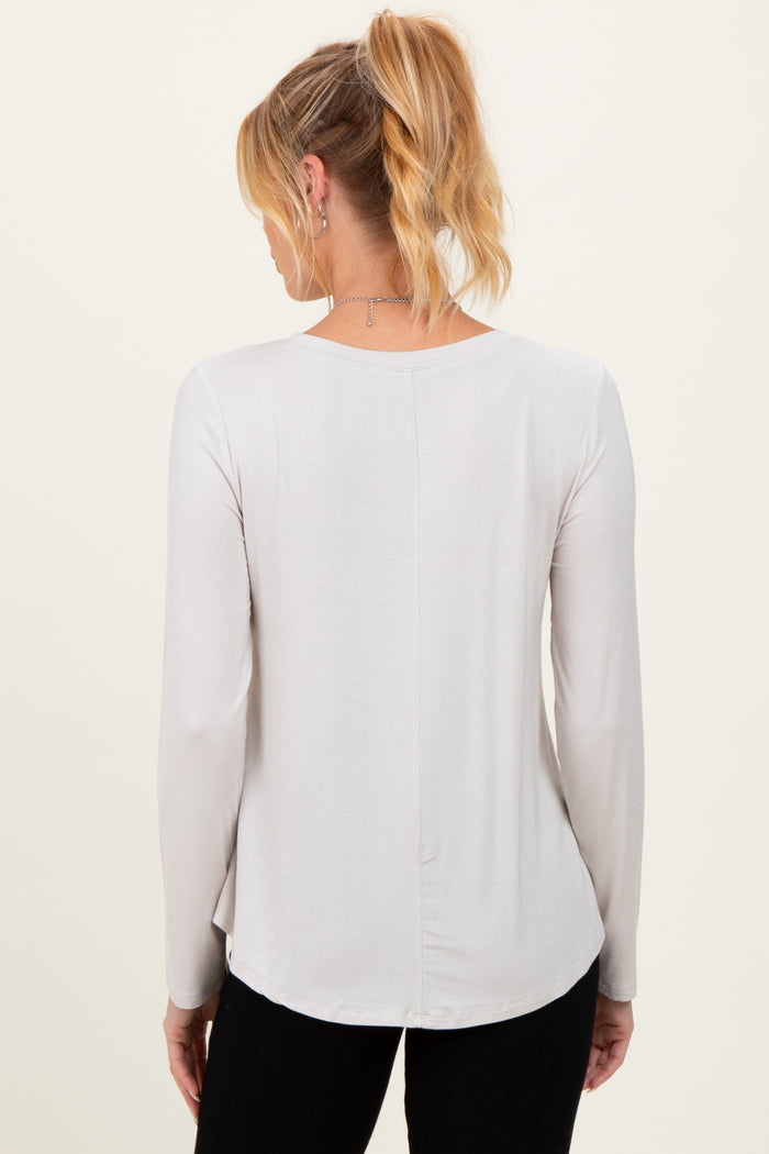woman wearing a light gray long sleeve maternity top, viewed from the back with a slightly curved hem