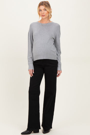 woman wearing a gray maternity sweater and black pants with a visible baby bump