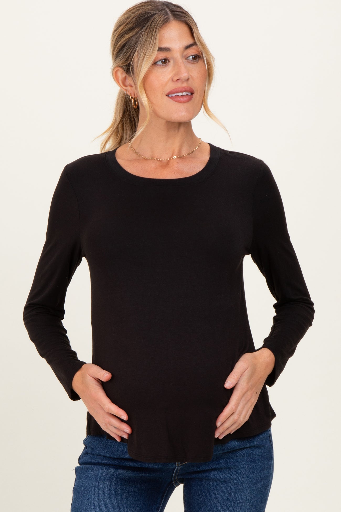 woman wearing a black long sleeve maternity top and holding her baby bump