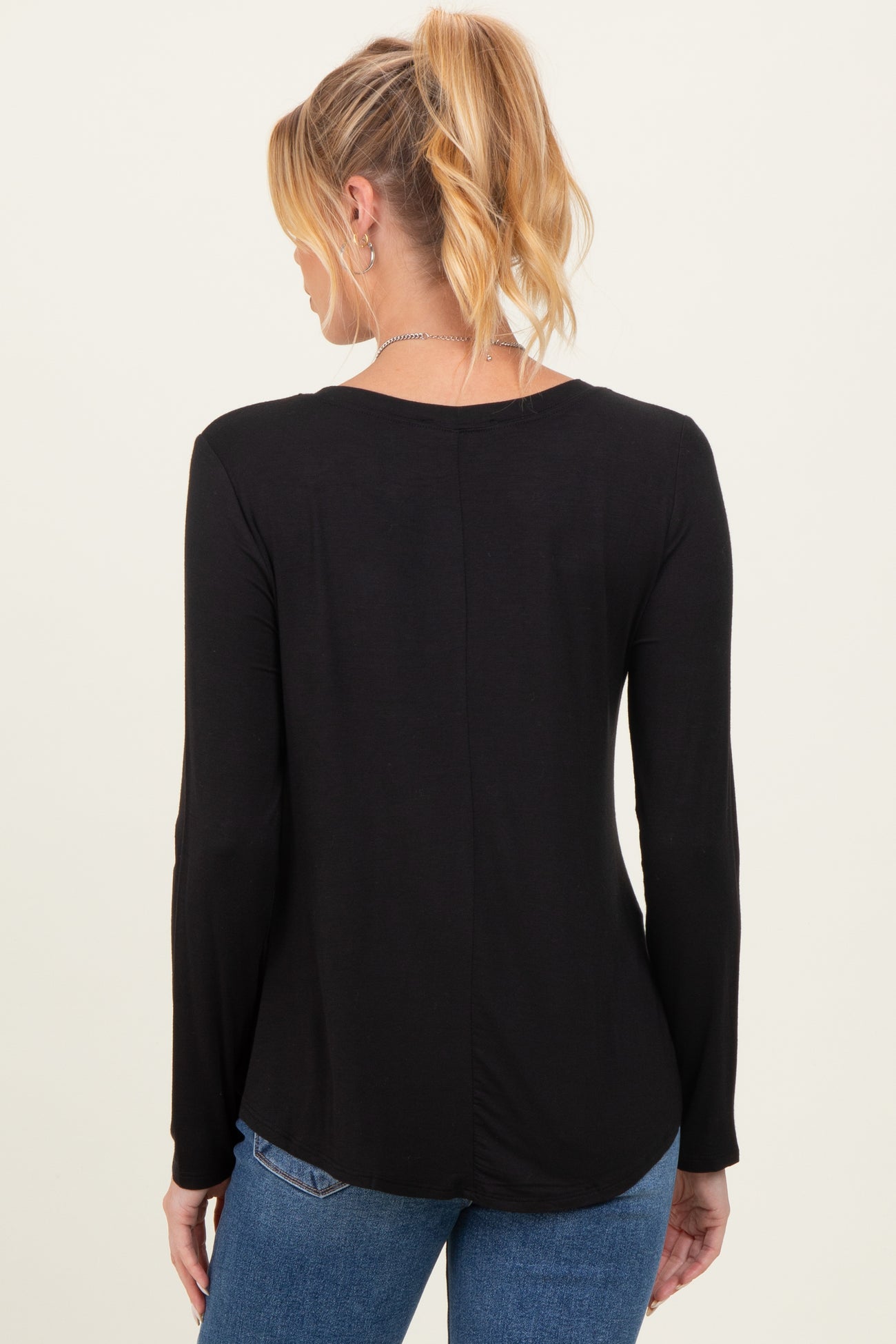 woman wearing a black long sleeve maternity top, seen from the back, styled with casual jeans