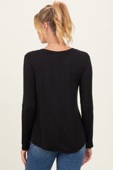 woman wearing a black long sleeve maternity top, seen from the back, styled with casual jeans