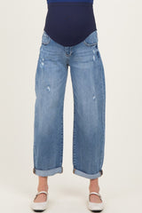 woman wearing a pair of light blue distressed maternity jeans with a wide leg and cuffed hem