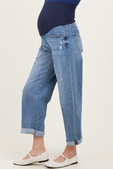 woman wearing distressed light blue maternity boyfriend jeans with rolled cuffs and a navy top, showing her baby bump