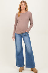 woman wearing a mauve long sleeve maternity top and wide-leg blue jeans showing her baby bump