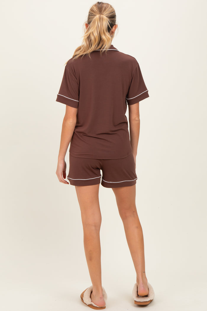 woman wearing a brown maternity short pajama set with white trim, viewed from the back