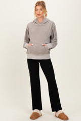 woman wearing a gray maternity hoodie with a front pocket and black ribbed pants, styled casually with fuzzy slippers
