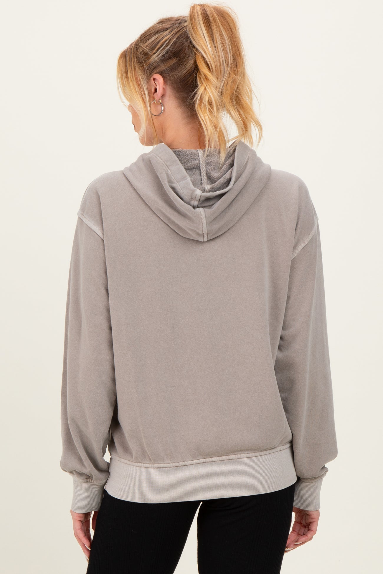 woman wearing a gray maternity hoodie with a relaxed fit and a hood, showing the back view