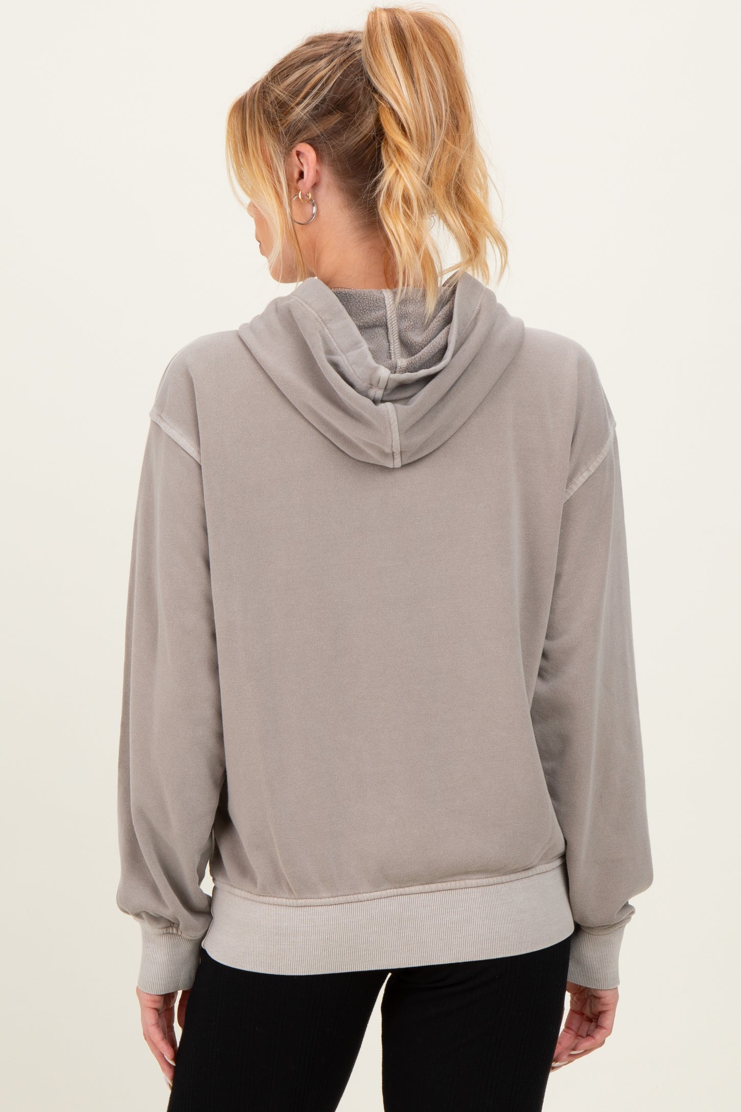 woman wearing a gray maternity hoodie with a relaxed fit and a hood, showing the back view