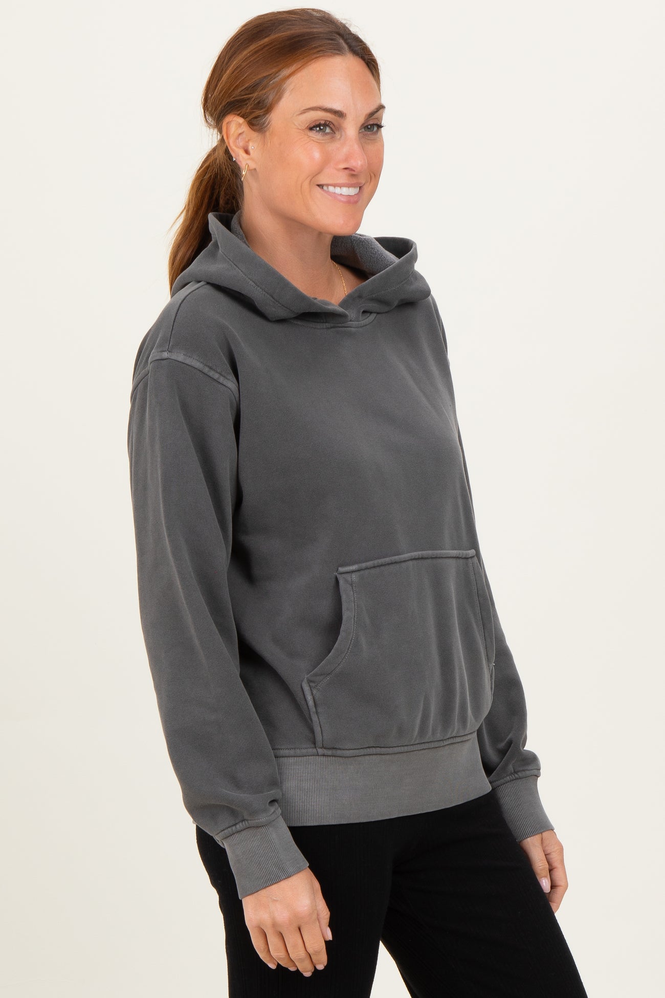 woman wearing a dark gray oversized hoodie with a kangaroo pocket and a high neck