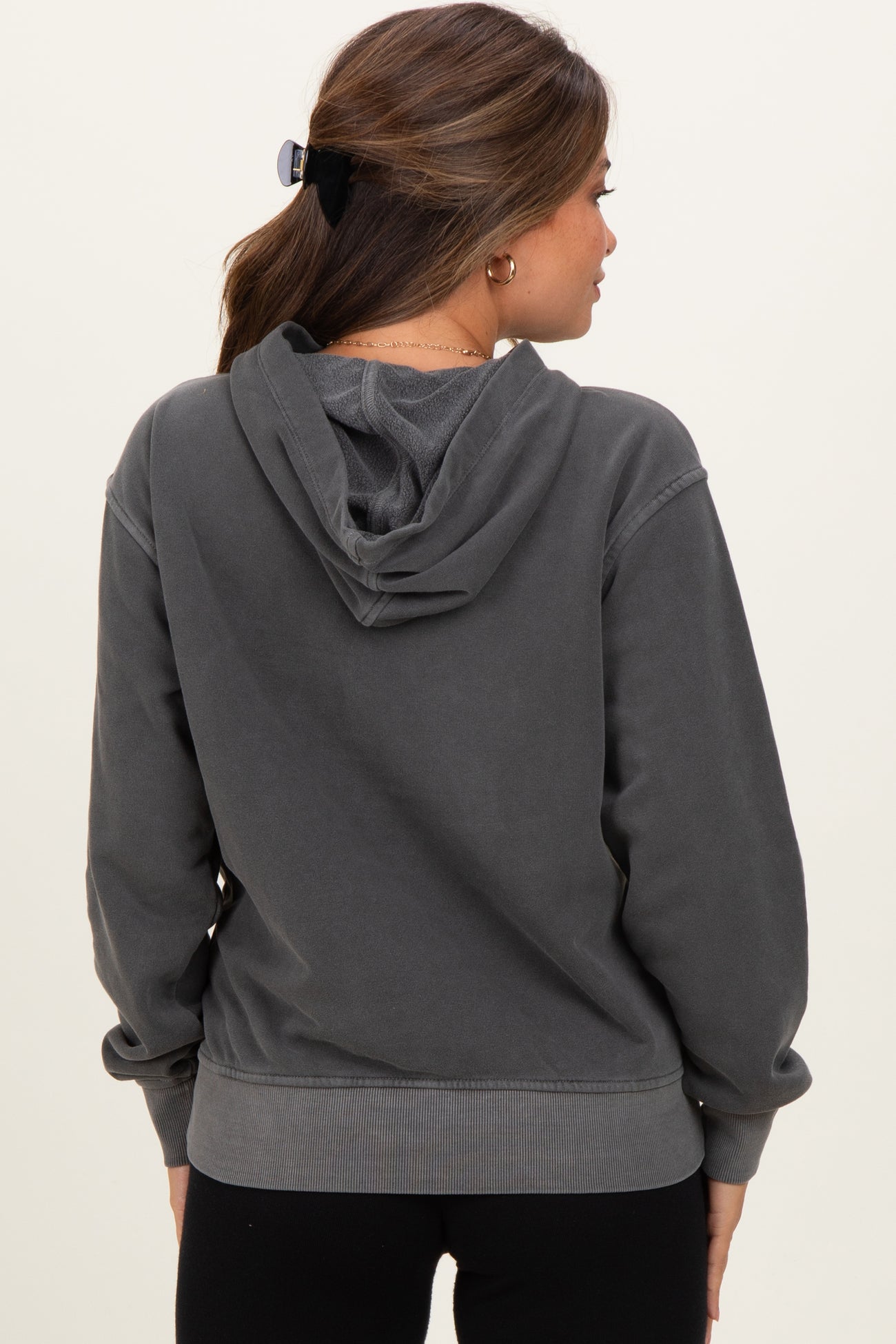 woman wearing a dark gray maternity hoodie with a relaxed fit and a hood, showing the back view