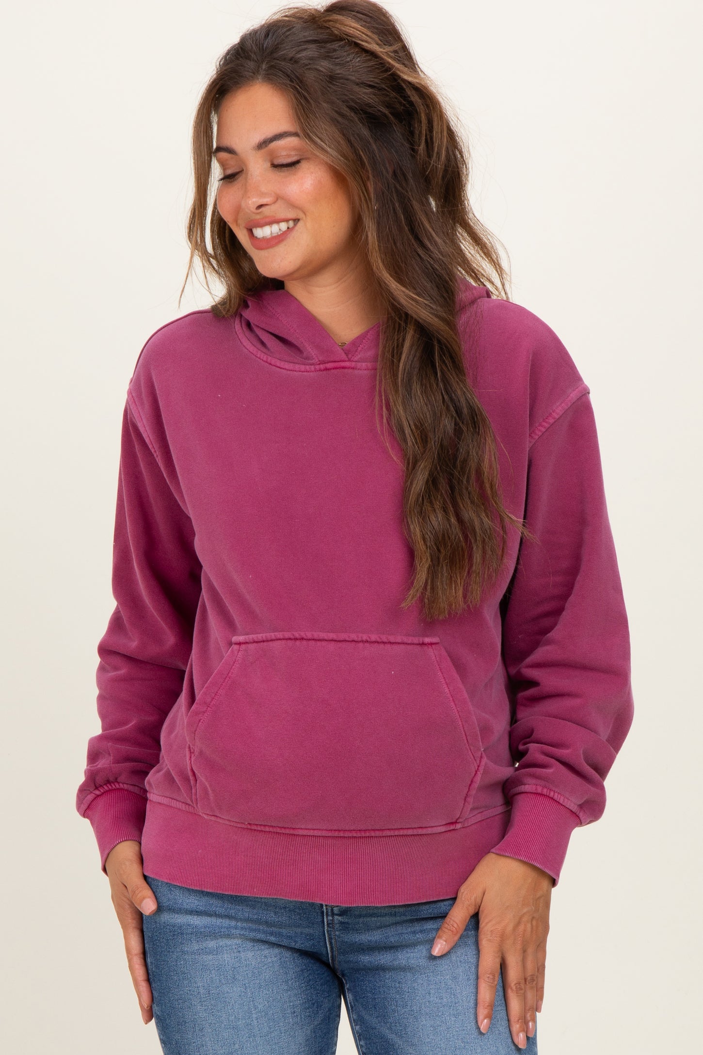 woman wearing a raspberry pink maternity hoodie with a front pocket and relaxed fit