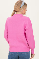 woman wearing a bright pink oversized knit sweater, showing the back and brushed hair in a ponytail