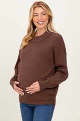 woman wearing a brown knit maternity sweater and holding her baby bump