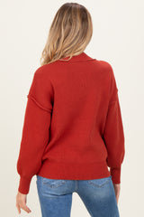 woman wearing a rust-colored maternity sweater with balloon sleeves and ribbed detailing, shown from the back