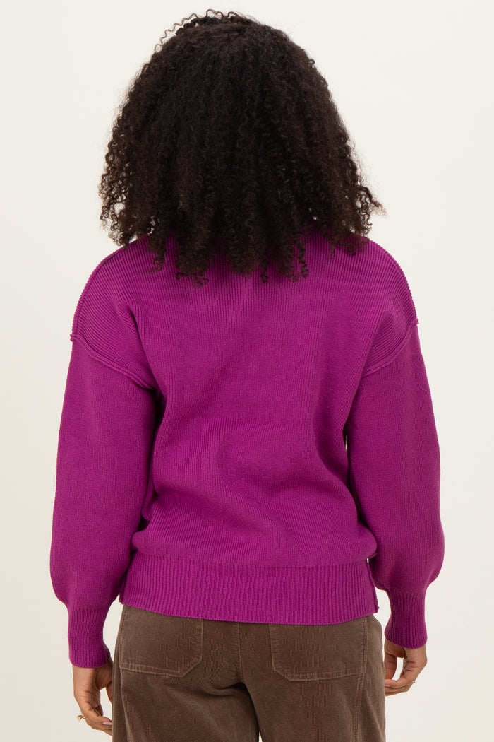 woman wearing a bright purple oversized sweater with puffed sleeves and ribbed hem, showing the back view
