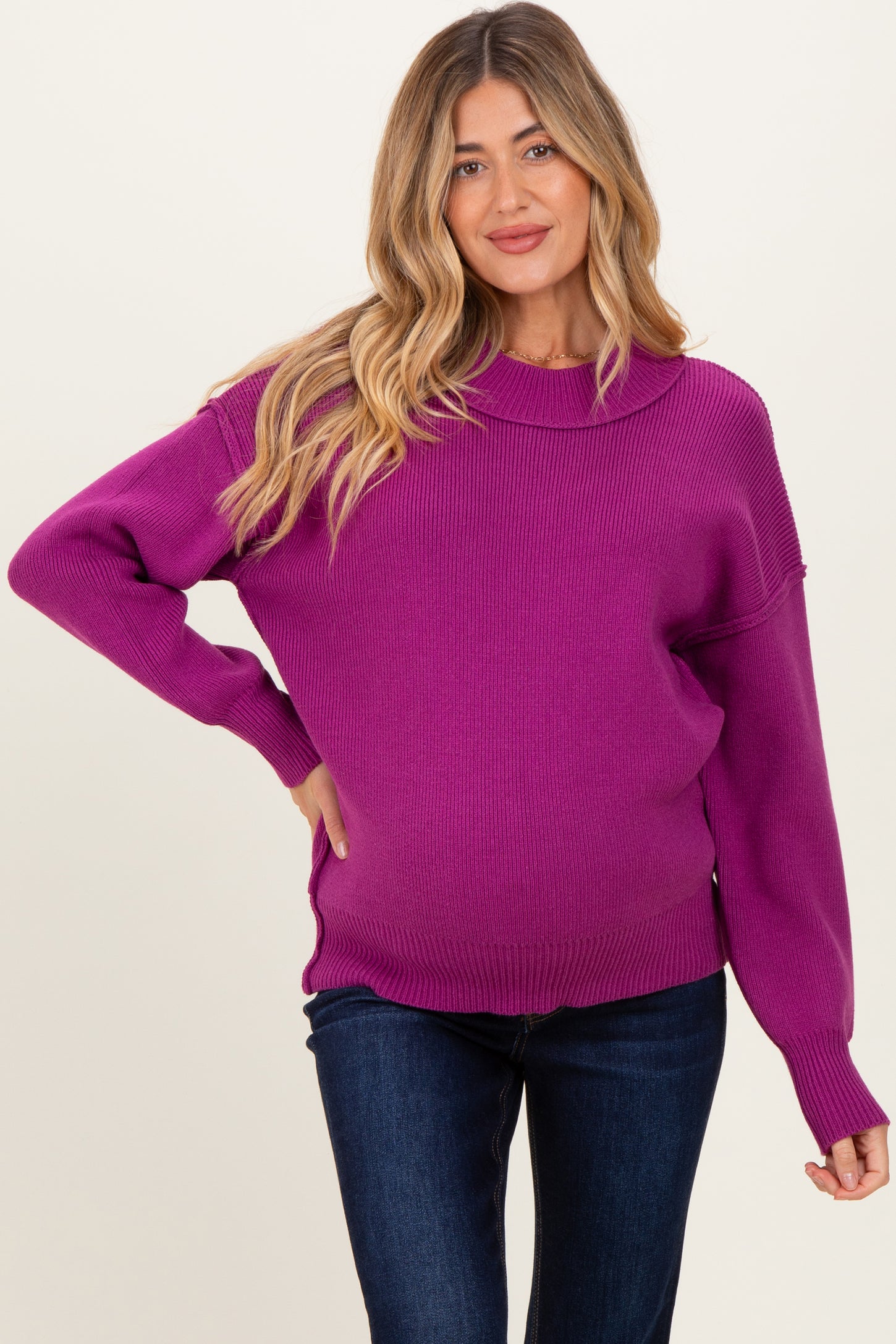 woman wearing a bright purple oversized maternity sweater with long sleeves and a visible baby bump