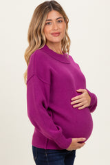 woman wearing a hot pink long sleeve maternity sweater and holding her baby bump
