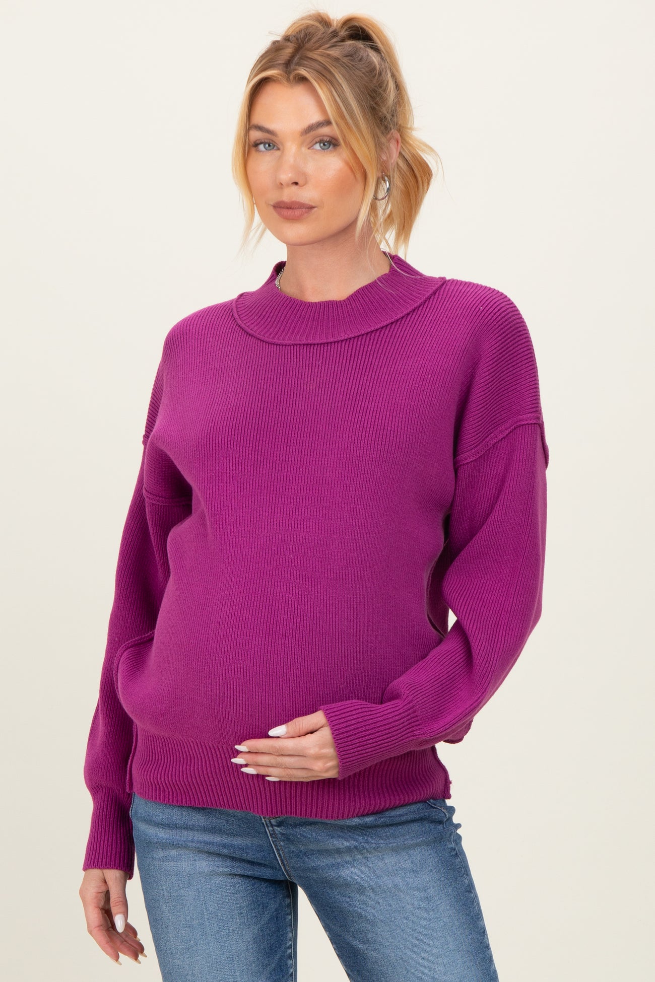 woman wearing a bright purple maternity sweater and holding her baby bump