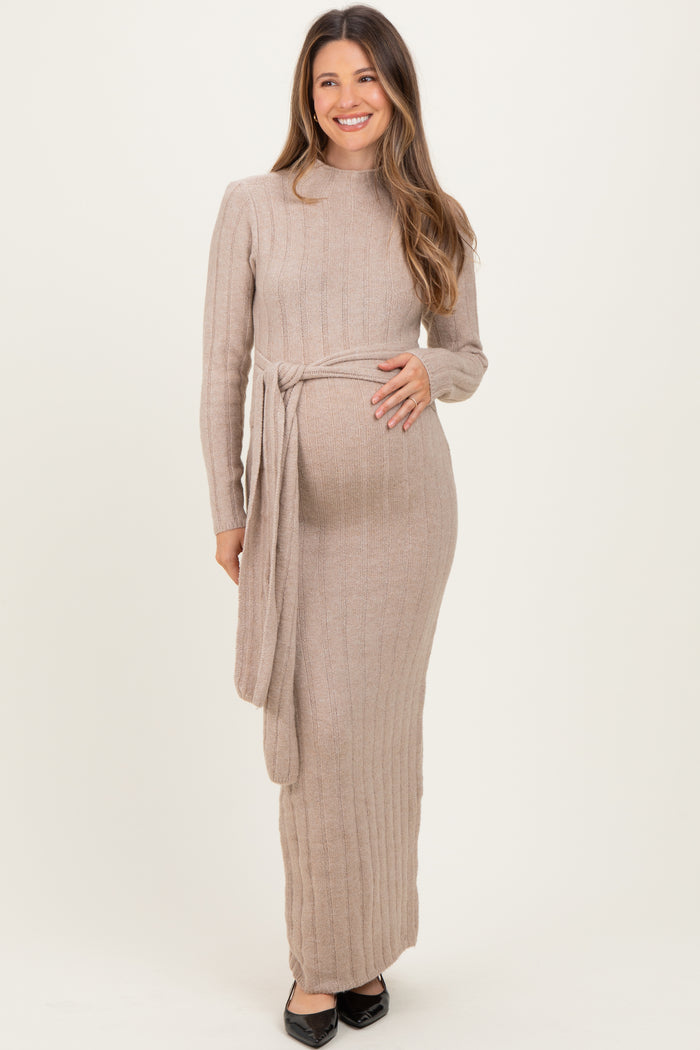 woman wearing a beige ribbed long sleeve maternity dress with a tie waist and visible baby bump