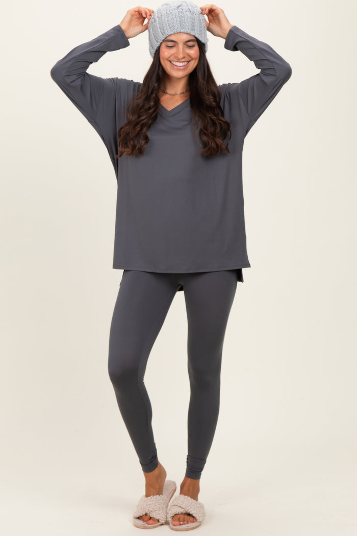 woman wearing a dark gray long sleeve top with a v-neck, matching leggings, and a knit beanie, styled with slippers