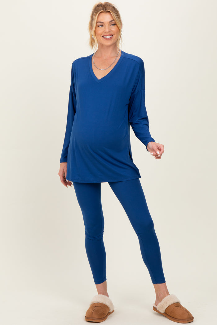 woman wearing a royal blue maternity tunic and leggings, showing her baby bump, paired with fuzzy slippers