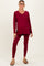 woman wearing a burgundy long sleeve maternity tunic top and matching leggings, showing her baby bump