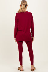 woman wearing a burgundy long sleeve maternity top and matching leggings, showing a relaxed fit from the back