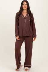 woman wearing a brown pajama set with white piping, featuring a button-up top and loose-fitting pants