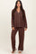 woman wearing a brown pajama set with white piping, featuring a button-up top and loose-fitting pants