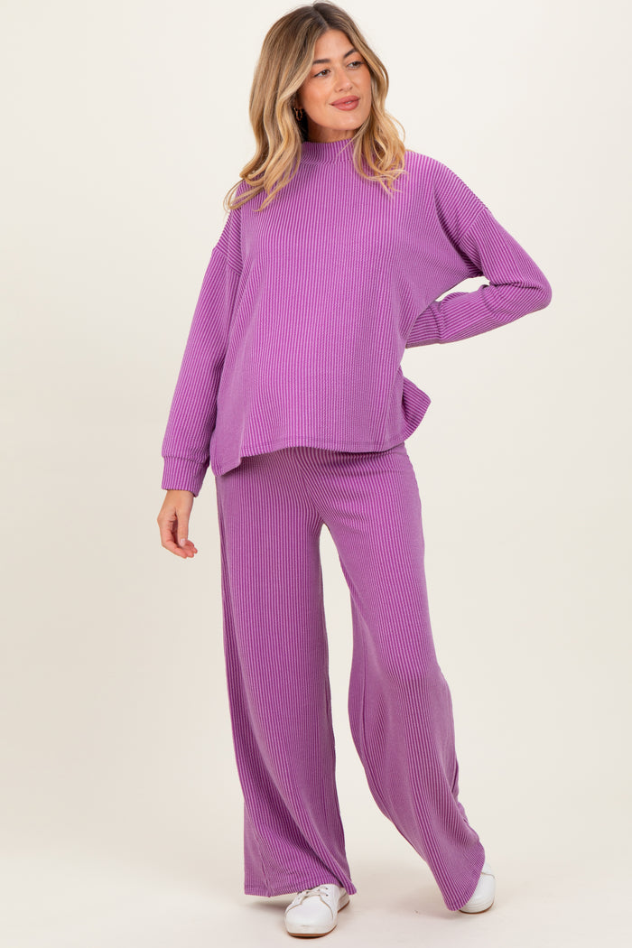 woman wearing a purple ribbed long sleeve maternity top and matching wide-leg pants, showcasing her baby bump