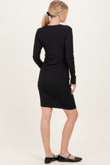 woman wearing a fitted black long sleeve dress, showing the back view with a sleek silhouette and knee-length hem