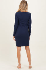 woman wearing a navy long sleeve maternity dress, showing the back view and a fitted silhouette